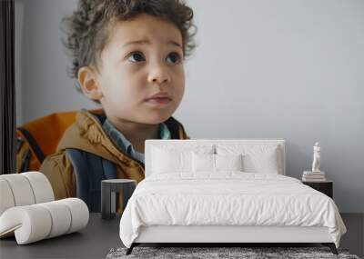 Precious youngster donning a backpack, exuding readiness and anticipation for their first day at school, set against a transparent white backdrop. Wall mural