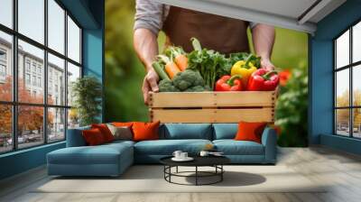 Farmer man holding wooden box full of fresh raw vegetables. Wall mural