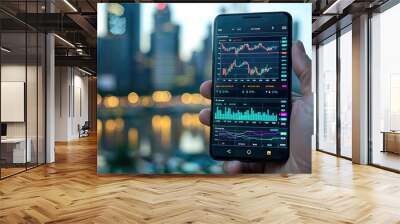 A hand holding a smartphone displaying stock market data with a blurry city skyline in the background. Wall mural