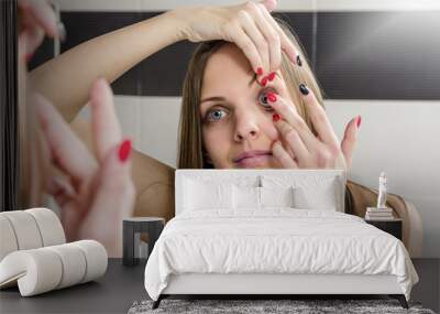 Young woman putting contact lens in her eye close up Wall mural