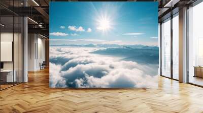 Aerial view of a mountain range above the clouds on a bright day Wall mural