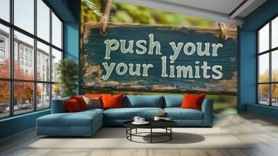 A rustic wooden sign with the inspirational message Push Your Limits hanging from a tree branch in a lush green forest Wall mural