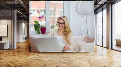 Junge Frau mit Laptop auf der Couch surft im Internet mit Wlan bucht Reise shoppt online Wall mural