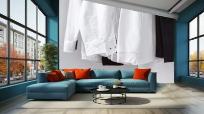 A close-up of the sleeves and cuffs of white clean shirts hanging in the closet. Black trousers in the wardrobe. Classic style clothes. Whitening. Office style. School uniform Wall mural