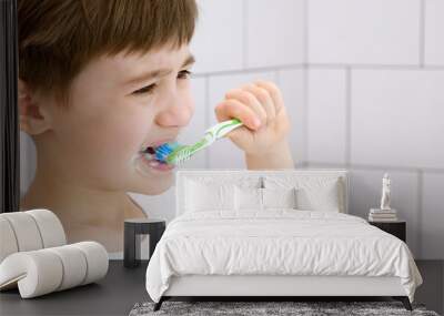 A cute little child brushes teeth. Green toothbrush. Daily morning hygiene procedures in a white bathroom. Portrait of beautiful caucasian 6 year old boy. Teeth brushing concept. Copy space. Close-up Wall mural