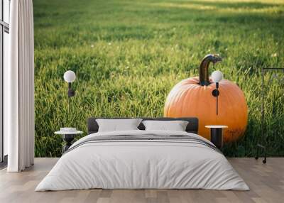 A field of green grass and three bright orange pumpkins of the new fall harvest in the sun. Beautiful landscape Wall mural