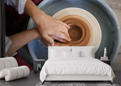 close-up female hands twist ceramic utensils on a potter's wheel top view Wall mural