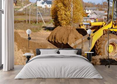 large yellow wheel loader aligns a piece of land for a new building. Preparation of the land for the auction. Leveling the landscape and adding sand for construction. Wall mural