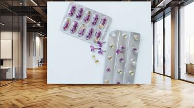 On a light background lie two blisters with capsules and lilac flowers inside. nearby are several capsules of different sizes and shapes and a lilac flower. Allergy medications Wall mural