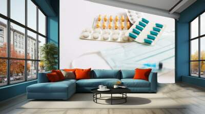 portion of pills on the background of a three-layer medical mask with rubber ear straps, a syringe and various medicines, tablets.The concept of medicine Wall mural