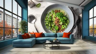 Vegetarian minestrone soup with green vegetables and lentils in gray plate on textured background, top view Wall mural