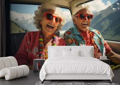 A very old happy couple with sunglasses and colourful summer clothes sits in the back of a car on a tour through the mountains. Wall mural