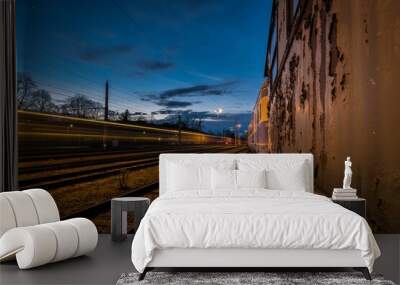 Beautiful shot of railway tracks by an old wall under a blue dark sky in the evening Wall mural