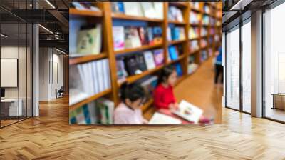 Blurred abstract background of bookshelves in book store, with children reading book in the store. Wall mural