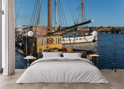 Sail boats at a quay an early sunny morning in autumn in Stockholm harbor at the island Skeppsholmen Wall mural