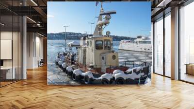 Snowy tire fenders on the side of an old tug boat, ice floaters a sunny winter day in Stockholm Wall mural