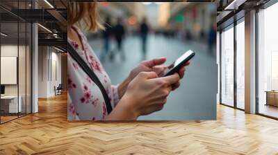 Close up of hands holding a smartphone, using a mobile phone for social media or online communication apps on a city street. Wall mural