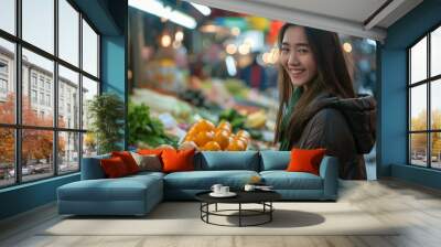 Young Asian woman carefully choosing fresh groceries at a Chinese street market Wall mural