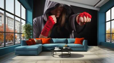 Female boxer makes a fight with a shadow, striking with silver boxing robe and red boxing wraps, black background. Strong and confident, she will be a champion. Wall mural