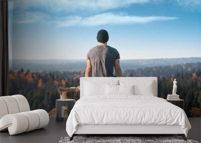 A man sits on a lookout point above the forest. Back view. Wall mural