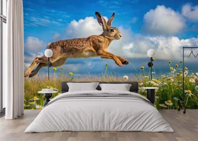 A brown hare bounds with freedom through a vibrant field of wildflowers, surrounded by a kaleidoscope of colors in the blue sky and puffy white clouds. Wall mural