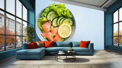 Bowl of salted salmon with fresh lettuce, cucumbers and lemon slices. Ketogenic-friendly lunch. Wall mural