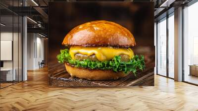 Juicy burger with melted cheese and greens on rustic wooden table. Tasty fast food for lunch Wall mural