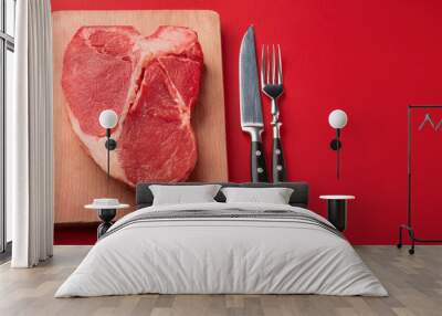 Juicy raw steak and cutlery on red background. Fresh uncooked meat. Cooking and culinary Wall mural