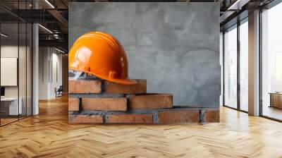 Orange hard hat on brick wall. Safety construction helmet. Builder protection concept. Wall mural