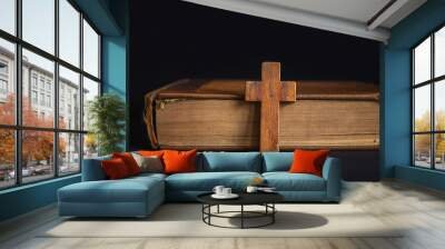 Wooden cross on closed old bible, dark backdrop. Christian faith, religion, culture. Prayer seeking Wall mural