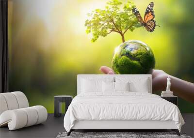 A hand holding a globe with a tree and a butterfly on it Wall mural