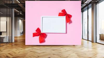 Empty picture frame and wooden date calendar with two red ribbons on purple background. Creative and cool celebration of love concept Wall mural