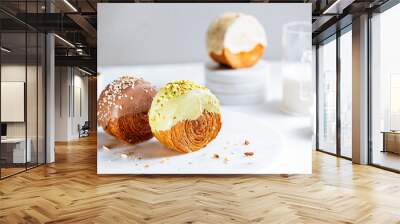 Fusion croissant called Cromboloni invented in New York. Round puff pastry filled with cream, and glazed with white, milk chocolate or pistachio. Crunchy and soft in the same time. Bright background.  Wall mural