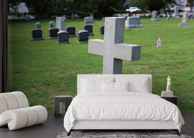 Cross shaped crucifix tombstone headstone in cemetery with gravestones in background Wall mural