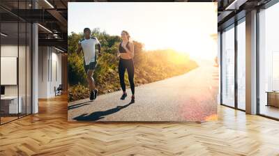 taking their run out on the open road. shot of a fit young couple going for a run outdoors. Wall mural