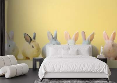 A group of pastel-colored bunnies lined up on a soft yellow background Wall mural