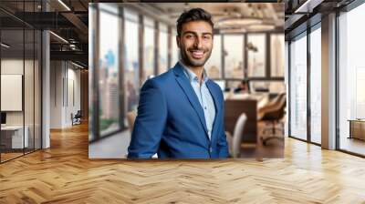 Portrait of a handsome businessman in a blue suit, smiling at the camera, with a modern office interior and cityscape in the background, copy space on the right. Wall mural