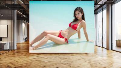 Young woman in red bikini relaxing by the serene ocean waters Wall mural