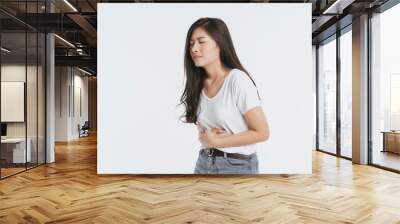 Asian woman unhappy looking sick, suffers from stomach ache stomachache isolated white background because of menstruation and eating spoiled food, Chronic gastritis. Abdomen bloating concept Wall mural