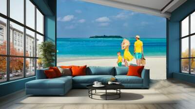 Family on beach, young couple in yellow with three year old boy. Summer vacation at Maldives. Wall mural