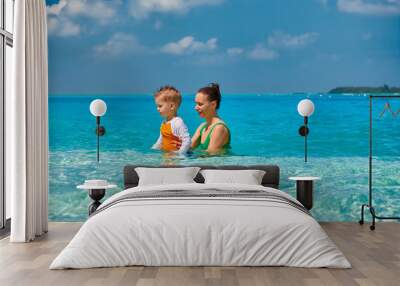 Toddler boy on beach with mother Wall mural