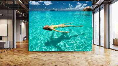 Woman in yellow bikini lying on water Wall mural