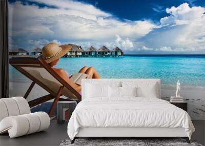 Young woman reading a book at beach Wall mural