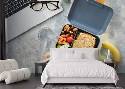 Healthy business lunch at workplace. Sandwich, vegetables, fruid and water lunch box on working desk with laptop, glasses. Wall mural