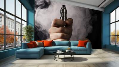 man holding electronic cigarette or vape device with smoke at the background. Wall mural