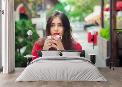 young woman thinking holding coffee on a trendy cafe terrace Wall mural