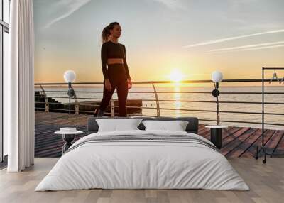 A sports woman with a prosthesis stands on the bridge in the morning at sunrise. Copy space. Wall mural