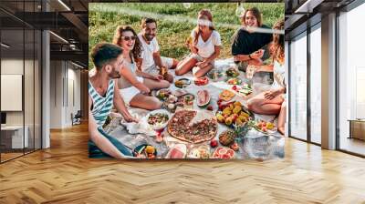 Group of friends having picnic in a park on a sunny day Wall mural