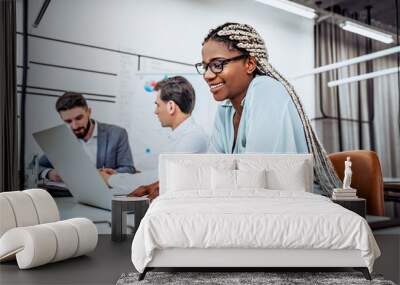 I love my job! A young American business woman works in an office with colleagues in the background. Wall mural