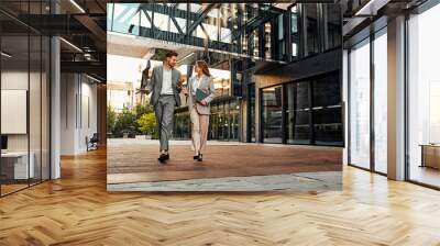 On the way to the office. Full-length shot of two stylish successful full-faced handsome people walking around the business center and discussing the project while gesturing with their hands. Wall mural